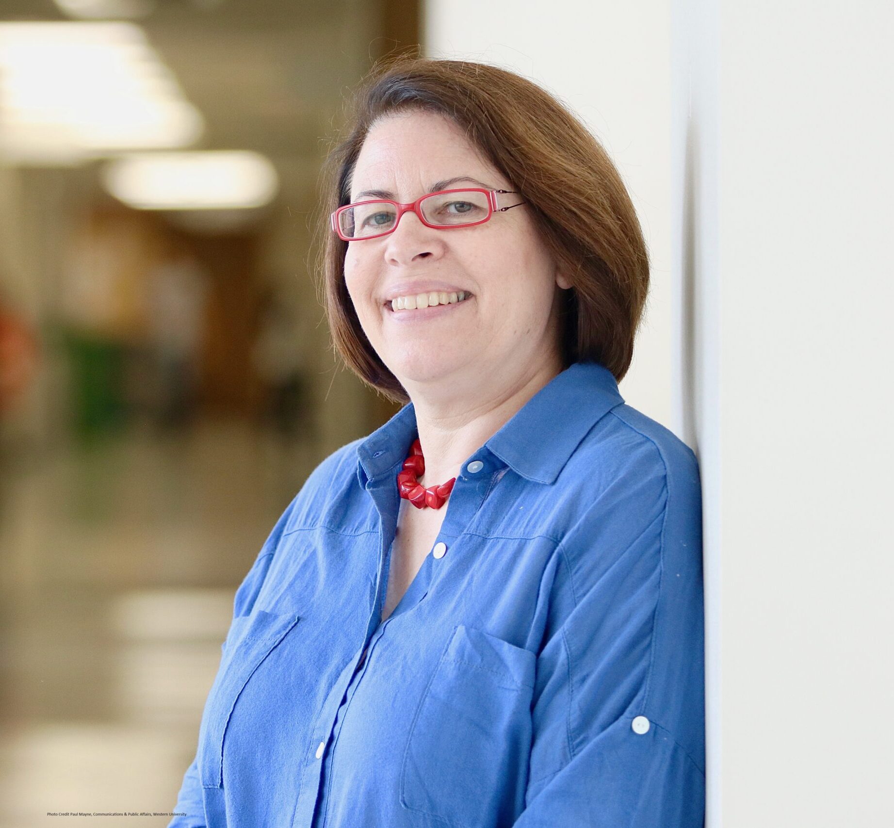 Woman comforting an emotional young teenage girl sitting with her legs crossed on a sofa and crying